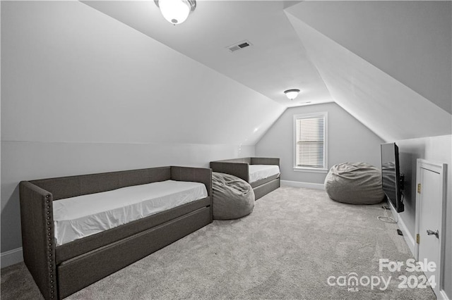 bedroom with light colored carpet and lofted ceiling