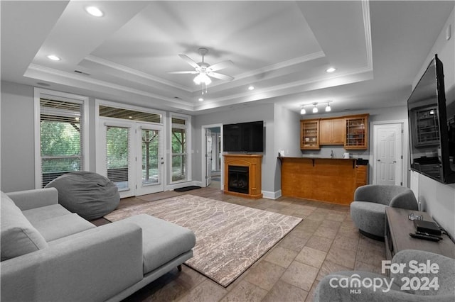 living room featuring ceiling fan, a raised ceiling, and light tile floors