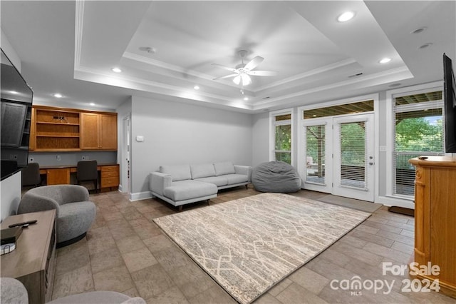 living room featuring ceiling fan and a raised ceiling