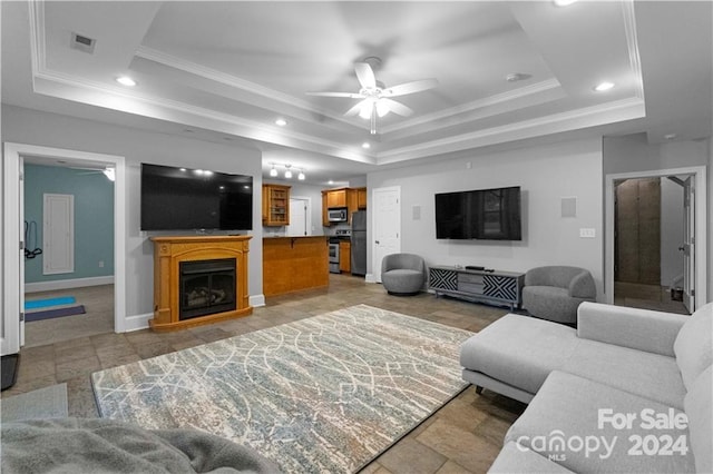 living room with tile floors, a tray ceiling, ceiling fan, and crown molding