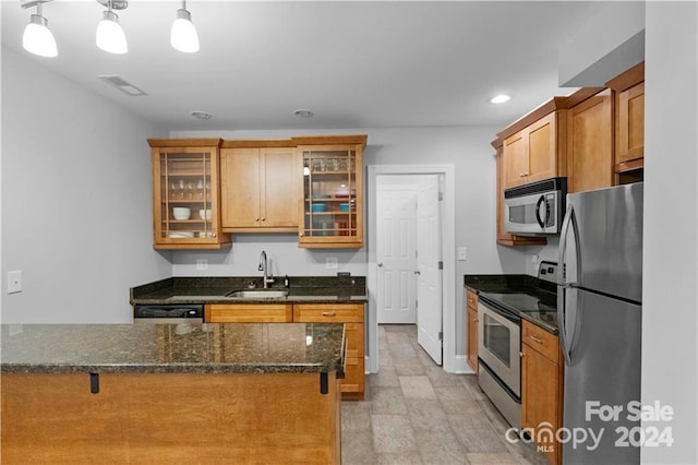 kitchen featuring decorative light fixtures, appliances with stainless steel finishes, sink, light tile floors, and dark stone counters