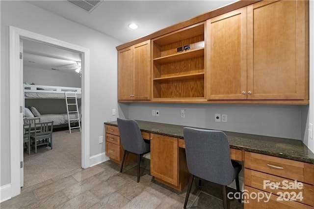 office space featuring built in desk, ceiling fan, and light tile floors