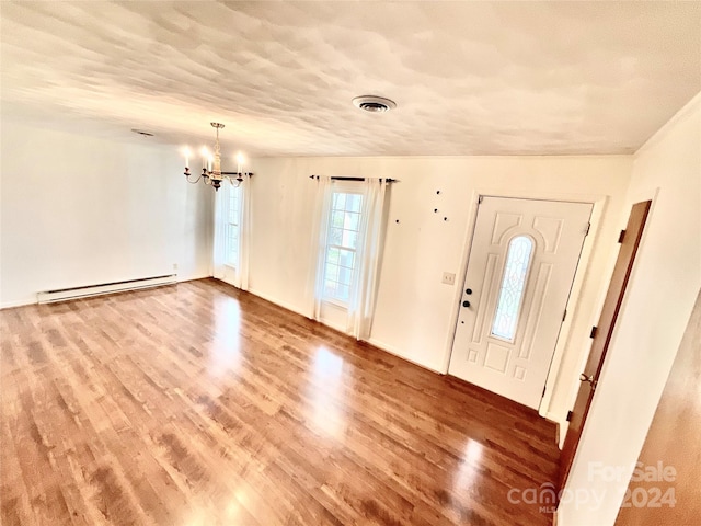 entrance foyer featuring wood-type flooring, a notable chandelier, and a baseboard heating unit