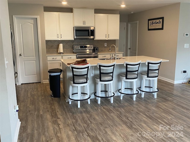 kitchen with appliances with stainless steel finishes, sink, a kitchen island with sink, dark hardwood / wood-style floors, and white cabinetry