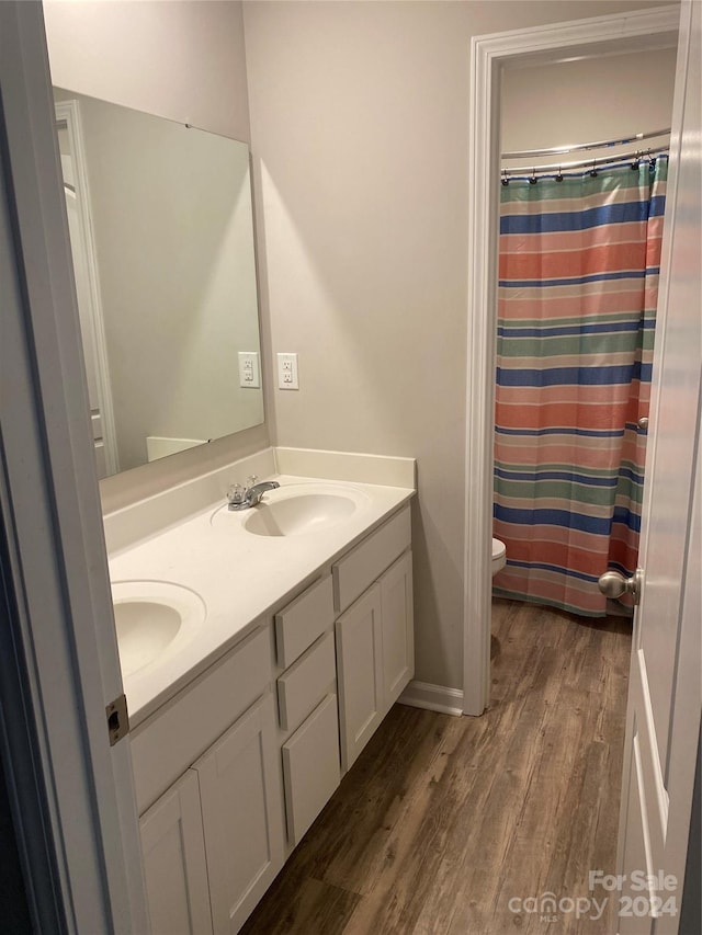 bathroom featuring hardwood / wood-style floors, dual vanity, and toilet