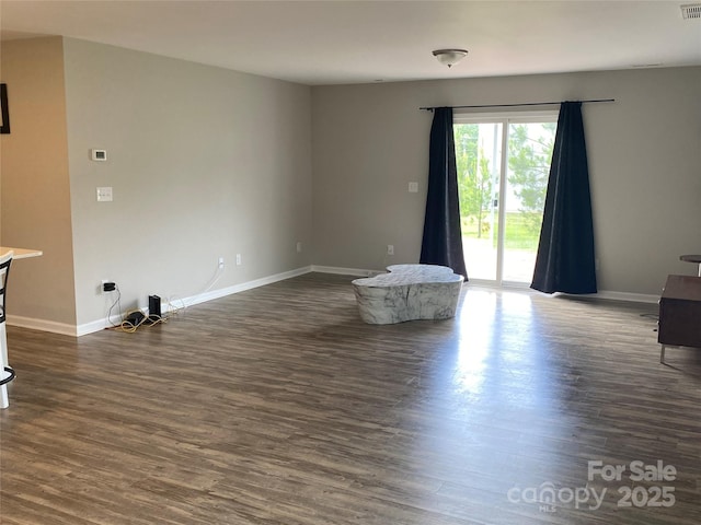 unfurnished living room with baseboards and dark wood-style flooring