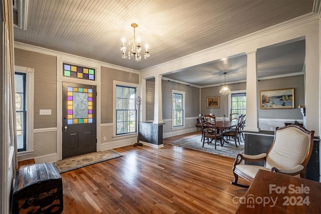 entryway featuring dark hardwood / wood-style floors, an inviting chandelier, decorative columns, and ornamental molding