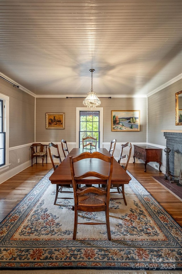 dining room featuring dark hardwood / wood-style flooring, crown molding, a fireplace, and a chandelier