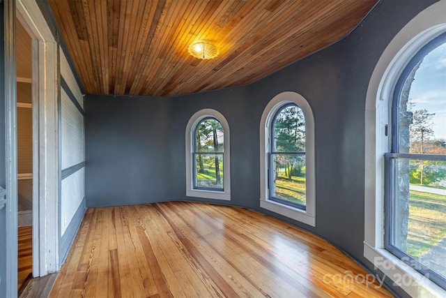 empty room with wood ceiling and light hardwood / wood-style flooring