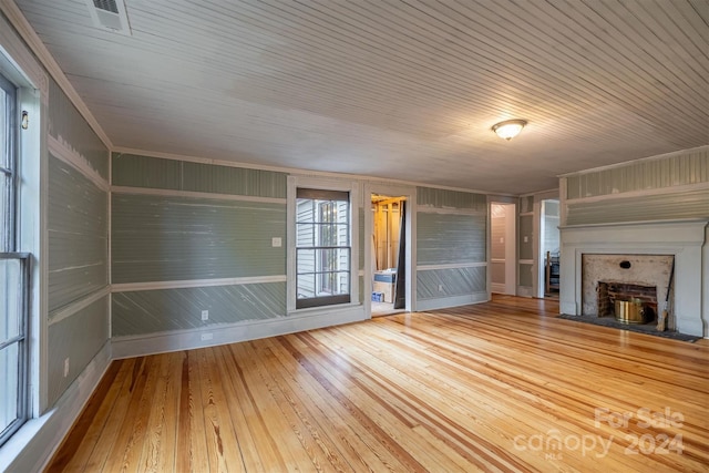 unfurnished living room featuring wooden walls, wood ceiling, and light hardwood / wood-style flooring