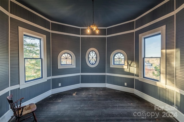 spare room with a healthy amount of sunlight, a chandelier, and dark hardwood / wood-style flooring