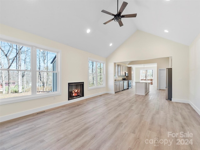 unfurnished living room with ceiling fan, a wealth of natural light, and light hardwood / wood-style floors