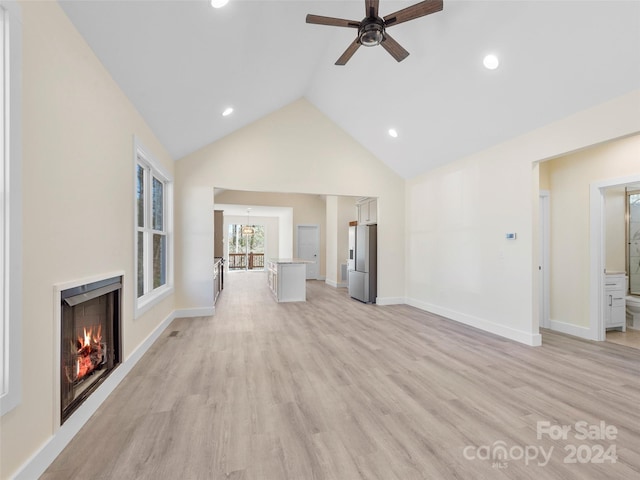 unfurnished living room with ceiling fan, high vaulted ceiling, and light hardwood / wood-style floors