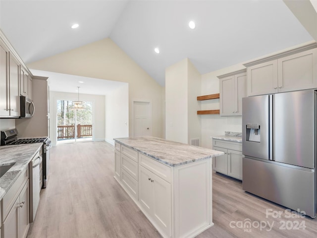 kitchen with light stone countertops, an inviting chandelier, appliances with stainless steel finishes, high vaulted ceiling, and light hardwood / wood-style floors