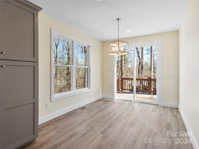 unfurnished room with light hardwood / wood-style floors and a notable chandelier