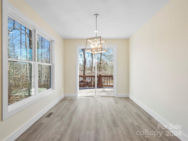 spare room featuring an inviting chandelier and light hardwood / wood-style flooring