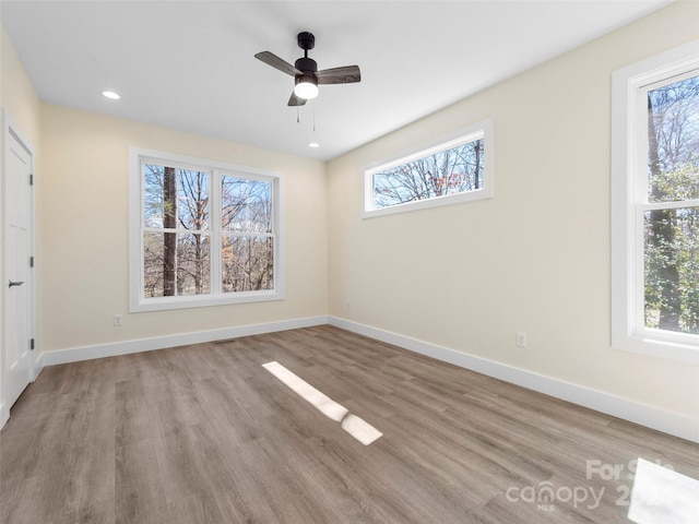 spare room with plenty of natural light, ceiling fan, and light wood-type flooring