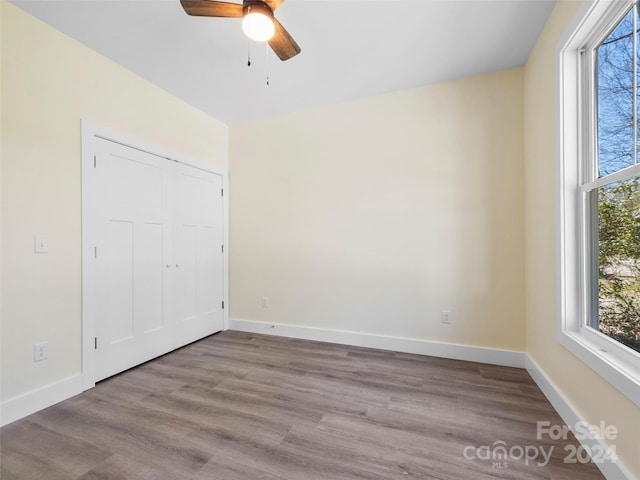 unfurnished bedroom with a closet, dark hardwood / wood-style floors, and ceiling fan