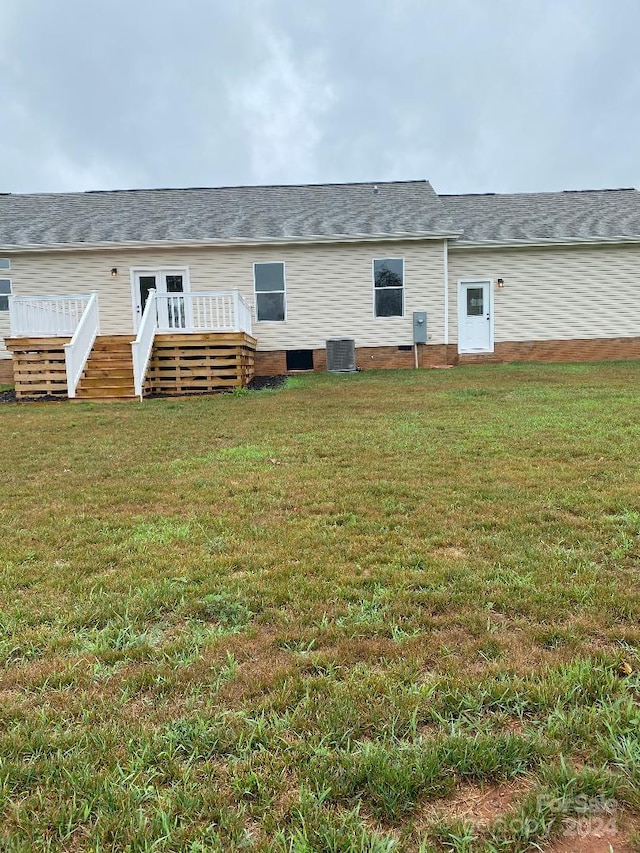 rear view of house featuring a wooden deck, central AC unit, and a lawn