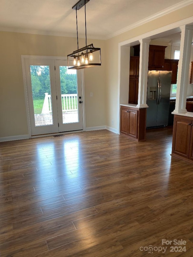 unfurnished room with ornate columns, dark hardwood / wood-style flooring, an inviting chandelier, and ornamental molding