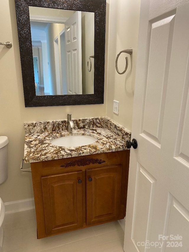 bathroom featuring tile flooring, vanity, and toilet