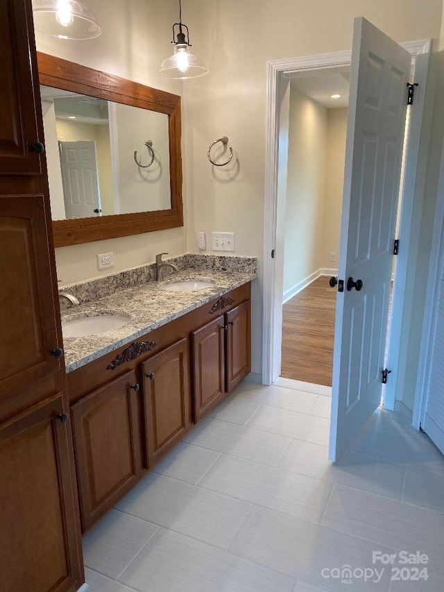 bathroom with vanity with extensive cabinet space, double sink, and tile flooring