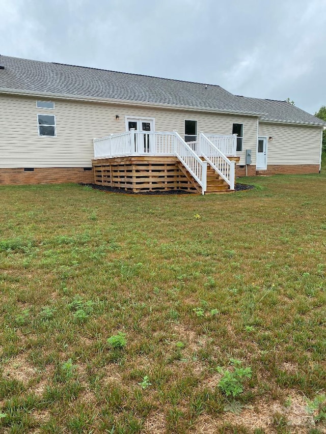 rear view of property featuring a deck and a lawn