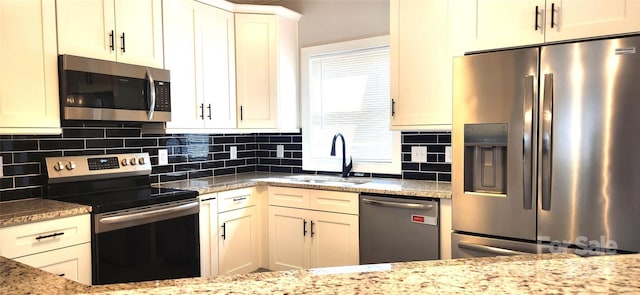 kitchen featuring tasteful backsplash, light stone countertops, sink, and appliances with stainless steel finishes