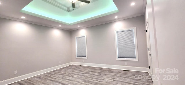 spare room with a raised ceiling, crown molding, ceiling fan, and hardwood / wood-style flooring