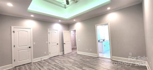 unfurnished bedroom featuring ensuite bathroom, hardwood / wood-style flooring, and crown molding