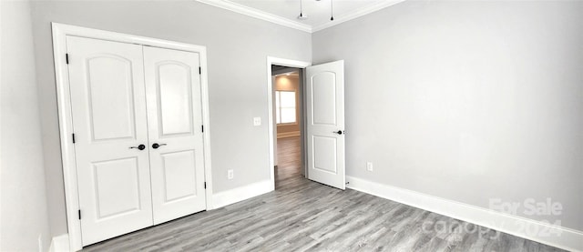 unfurnished bedroom featuring light hardwood / wood-style floors, ornamental molding, and a closet