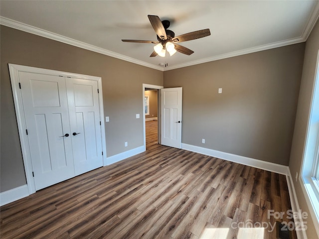 unfurnished bedroom with baseboards, a ceiling fan, wood finished floors, a closet, and crown molding