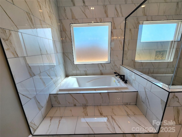 bathroom with tile walls, a garden tub, and marble finish floor
