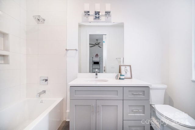 full bathroom with vanity, tiled shower / bath, toilet, and ceiling fan