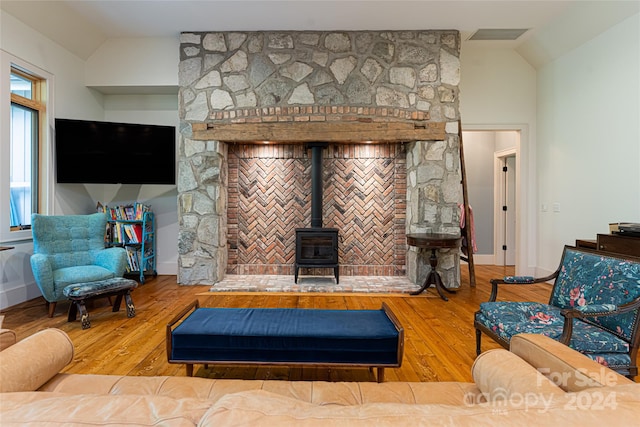 living room featuring a wood stove, wood-type flooring, and vaulted ceiling