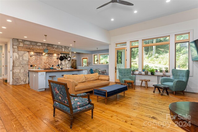 living room featuring light hardwood / wood-style flooring, indoor bar, and ceiling fan