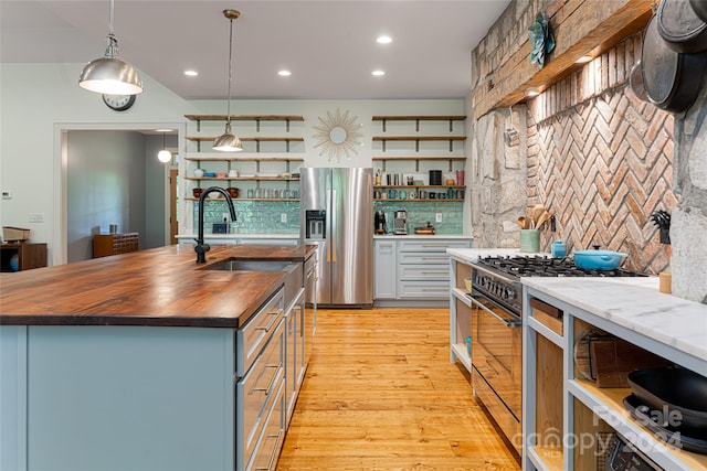 kitchen featuring sink, light wood-type flooring, wood counters, hanging light fixtures, and stainless steel appliances