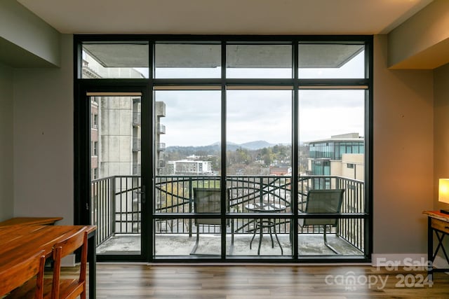 doorway to outside with a wall of windows, a mountain view, and hardwood / wood-style floors