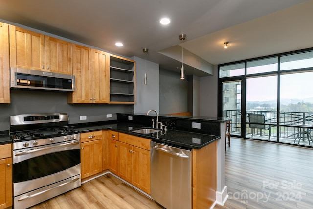 kitchen featuring decorative light fixtures, a wall of windows, stainless steel appliances, dark stone counters, and kitchen peninsula