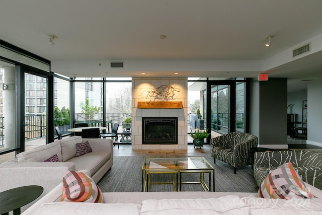 tiled living room with floor to ceiling windows and a tiled fireplace