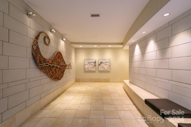 corridor featuring light tile patterned floors and tile walls