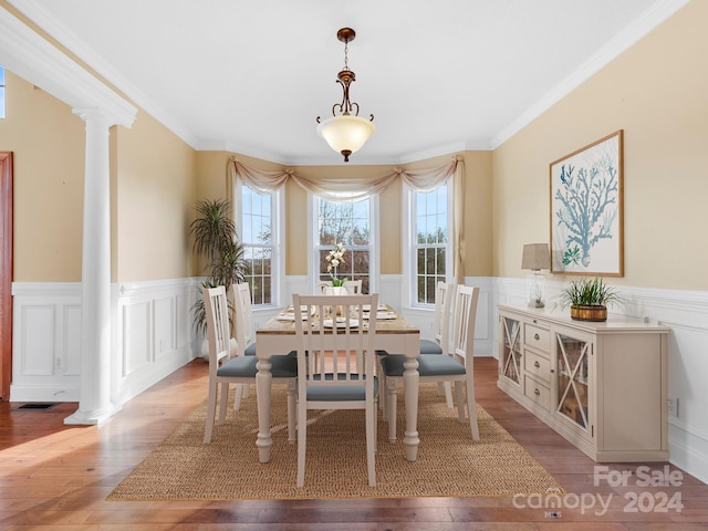 dining area with ornate columns, crown molding, and light wood-type flooring