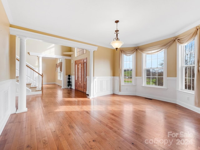 unfurnished room featuring light hardwood / wood-style floors, crown molding, and ornate columns