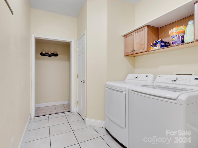 laundry room featuring washing machine and clothes dryer, cabinets, and light tile floors