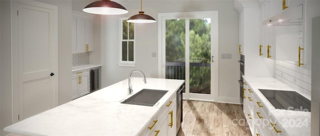 kitchen with sink, light hardwood / wood-style flooring, white cabinetry, hanging light fixtures, and light stone countertops