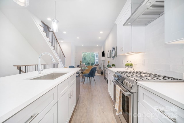 kitchen with premium range hood, appliances with stainless steel finishes, decorative light fixtures, white cabinetry, and sink