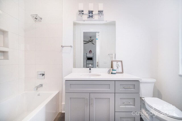 full bathroom featuring ceiling fan, vanity, tiled shower / bath combo, and toilet