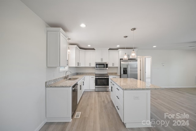 kitchen featuring white cabinets, a kitchen island, light wood-type flooring, and stainless steel appliances