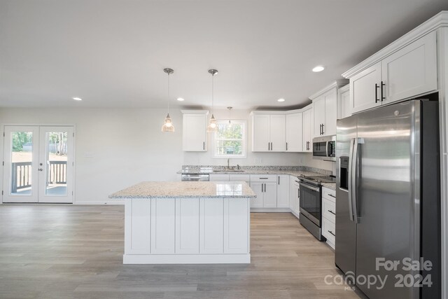 kitchen with light stone countertops, decorative light fixtures, light hardwood / wood-style flooring, stainless steel appliances, and white cabinets