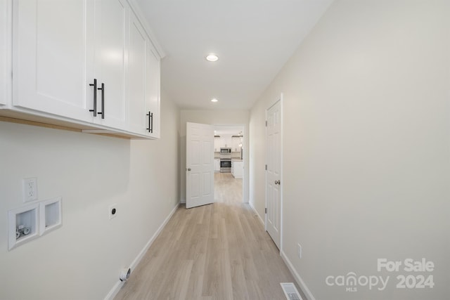 clothes washing area with cabinets, hookup for an electric dryer, and light hardwood / wood-style floors